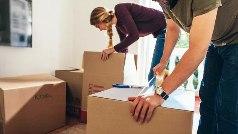 organizing belongings webp Couple packing boxes, symbolizing the careful organization of probate estate belongings after death. Contact Kid Breukelen Realty Group for professional assistance.