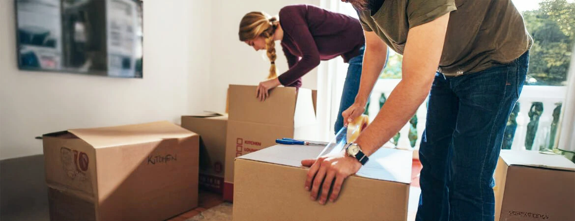 organizing belongings dt A couple carefully packing boxes, symbolizing the organization of probate estate belongings after death. This image reflects the process of managing items during probate. Reach out to Kid Breukelen Realty Group for expert help with estate management.